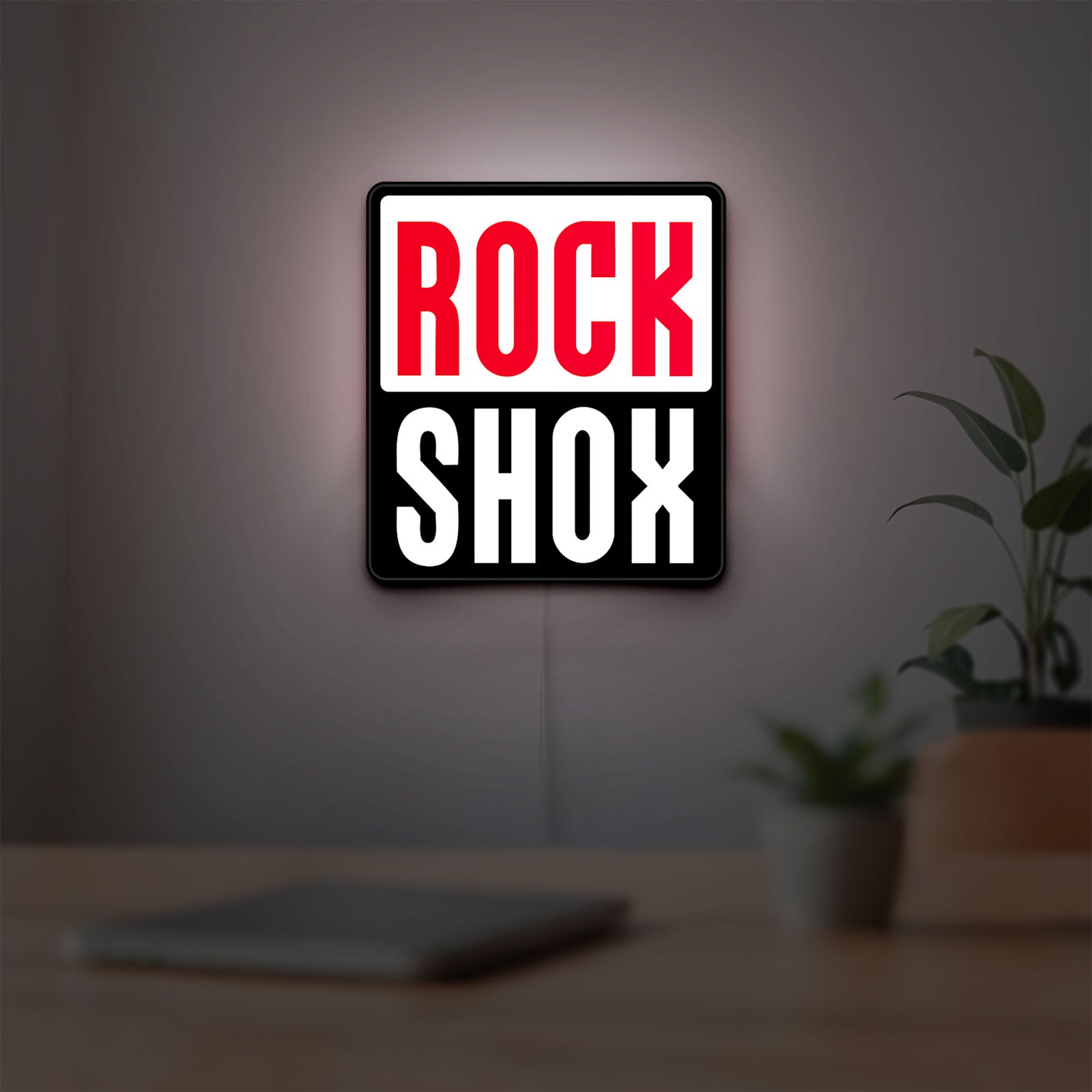 Rock Shox LED lightbox hanging on a room wall with soft white light