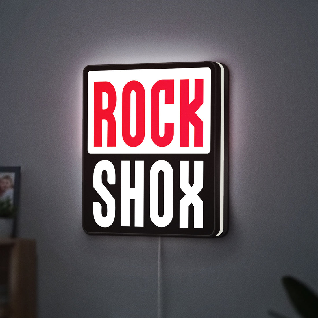 Rock Shox LED lightbox hanging on a wall with white glow