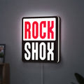 Rock Shox LED lightbox hanging on a wall with white glow