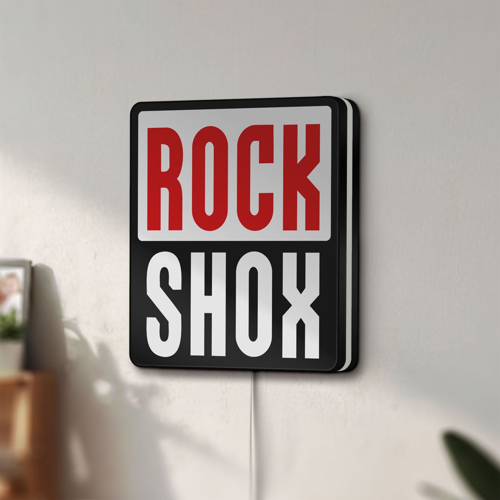 Unlit Rock Shox LED lightbox mounted on a wall in daylight