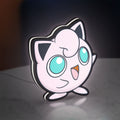 Jigglypuff LED lightbox standing on a desk from an angled side view with white glow