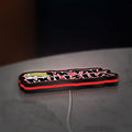 Metal Mulisha LED lightbox lying flat on a desk with red glow