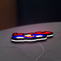 Superman S Shield LED lightbox lying flat on a desk with white glow
