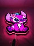 Pink Stitch LED Sign (30cm) - Illuminated flat lay angled view, unique wall art for desk and room decor
