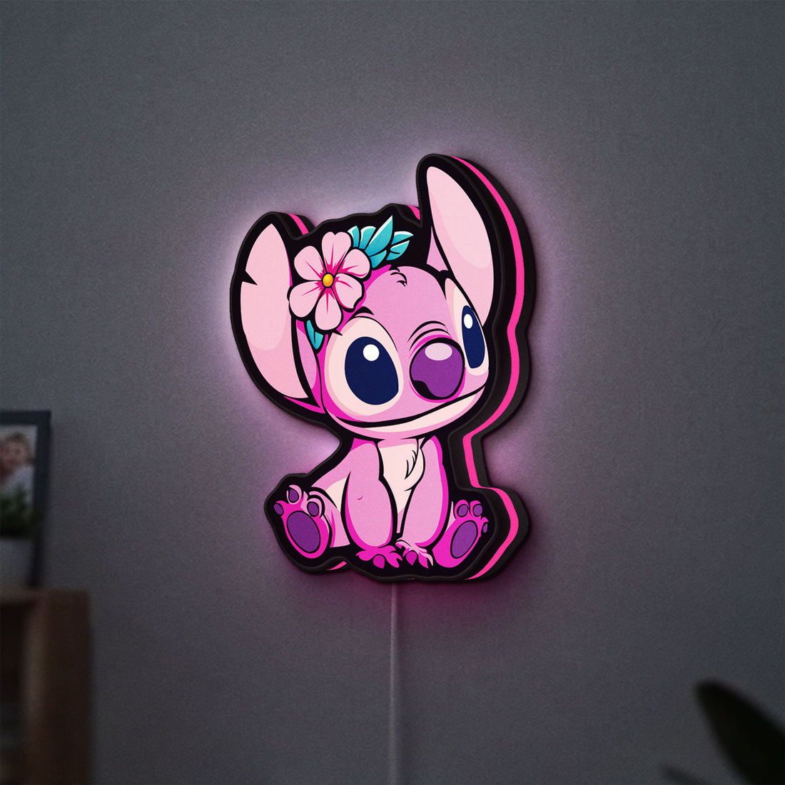 Pink Stitch LED lightbox hanging on a wall with pink glow