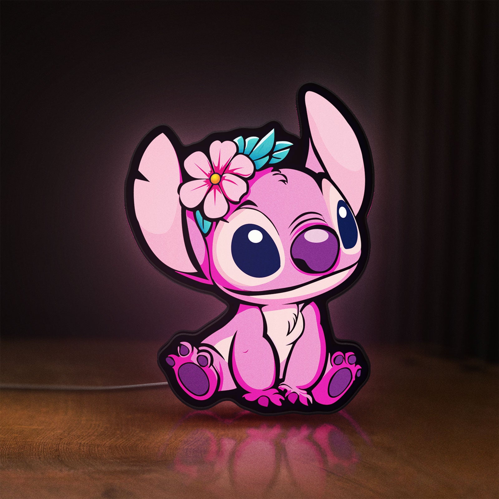 Front view of Pink Stitch LED lightbox sign glowing on a wooden desk