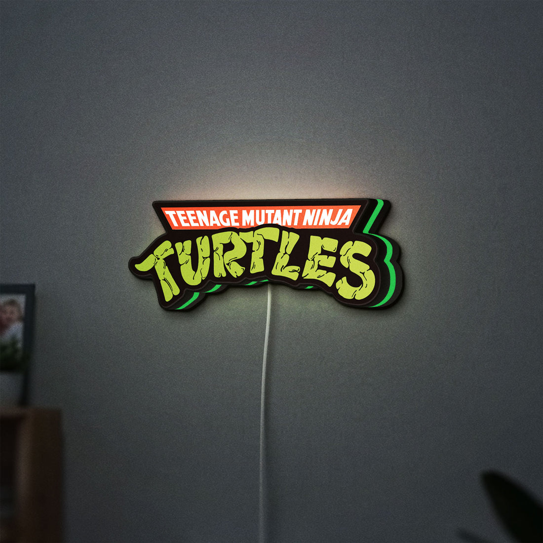 Turtles LED lightbox hanging on a wall with green glow