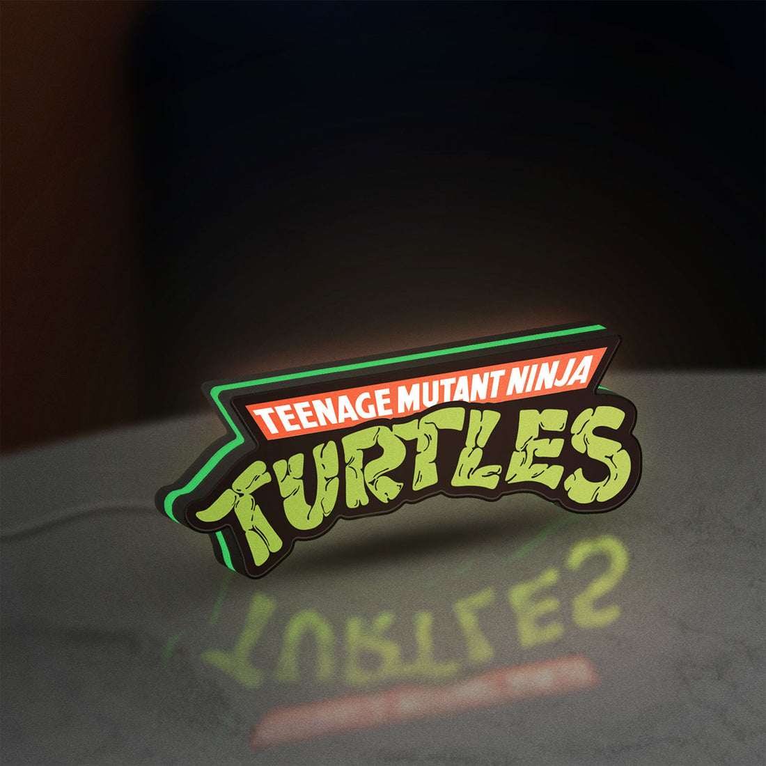 Turtles LED lightbox hanging on a wall with green glow