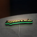 Turtles LED lightbox lying flat on a desk with green glow
