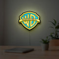 Warner Bros Shield LED lightbox hanging on a room wall with soft yellow light