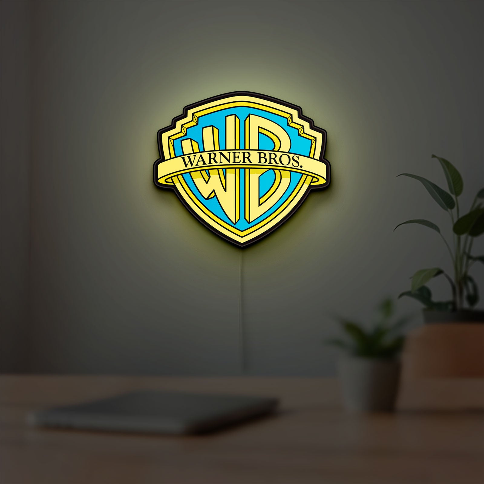 Warner Bros Shield LED lightbox hanging on a room wall with soft yellow light