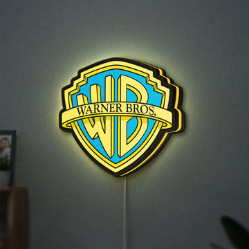 Warner Bros Shield LED lightbox hanging on a wall with yellow glow