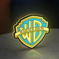 Warner Bros Shield LED lightbox standing on a desk from an angled side view with yellow glow