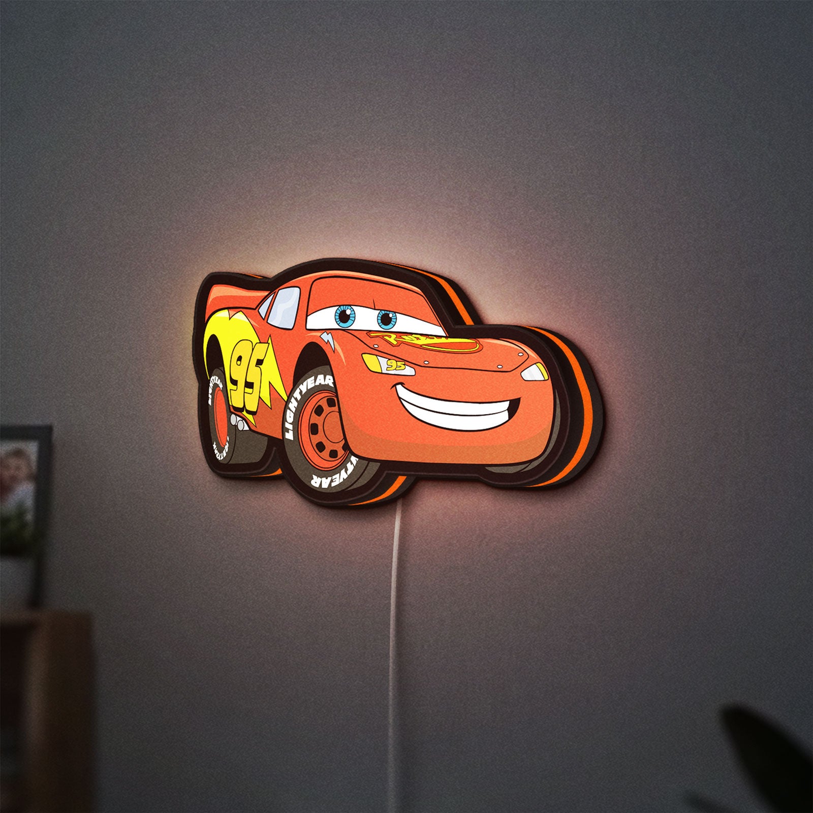 Lightning McQueen LED lightbox hanging on a wall with orange glow