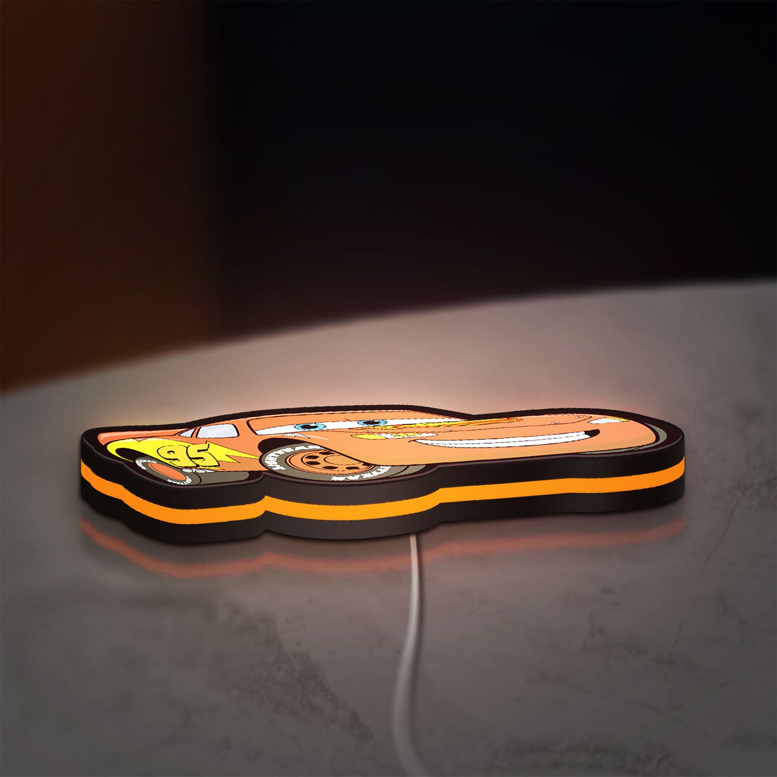 Lightning McQueen LED lightbox lying flat on a desk with orange glow