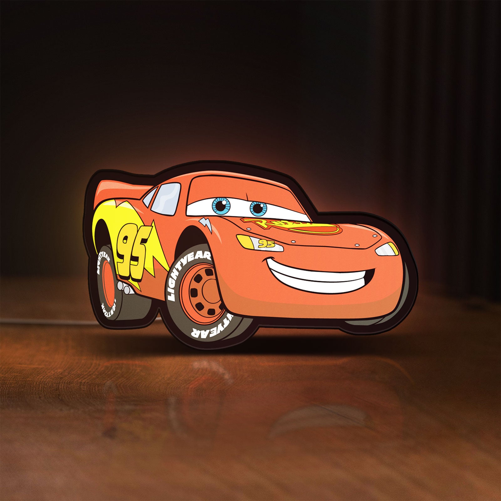 Front view of Lightning McQueen LED lightbox sign glowing on a wooden desk
