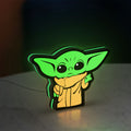 Grogu The Child LED lightbox standing on a desk from an angled side view with green glow