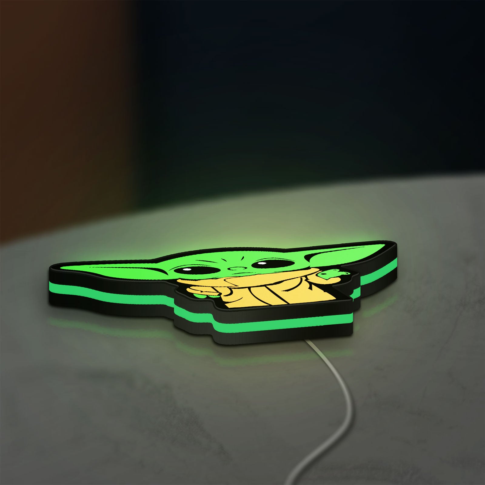 Grogu The Child LED lightbox lying flat on a desk with green glow