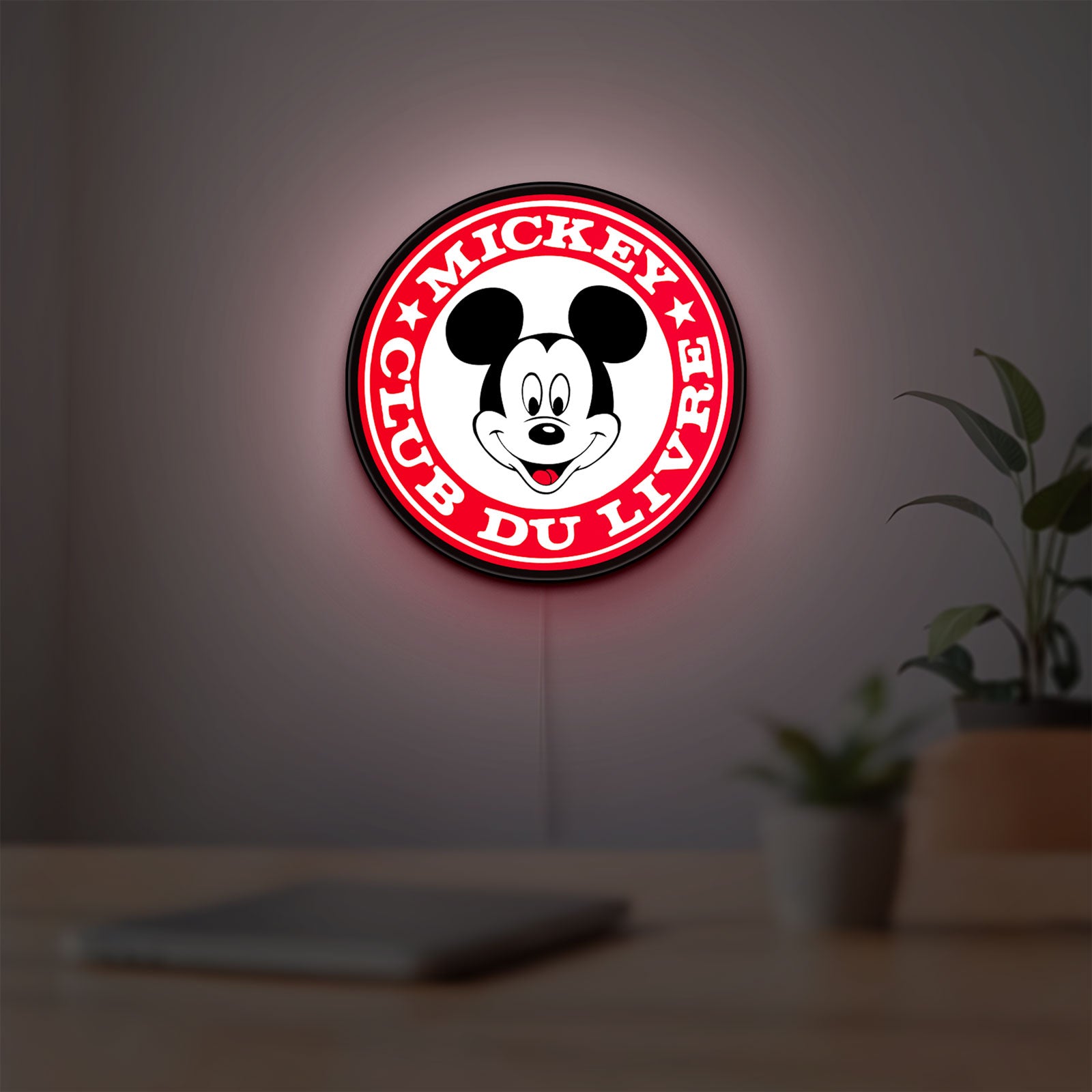 Mickey Club Du Livre LED lightbox hanging on a room wall with soft red light