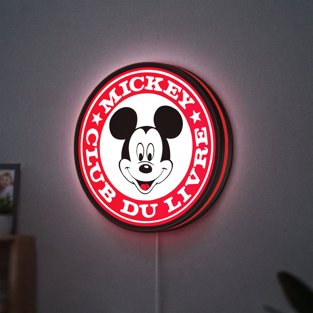 Mickey Club Du Livre LED lightbox hanging on a wall with red glow