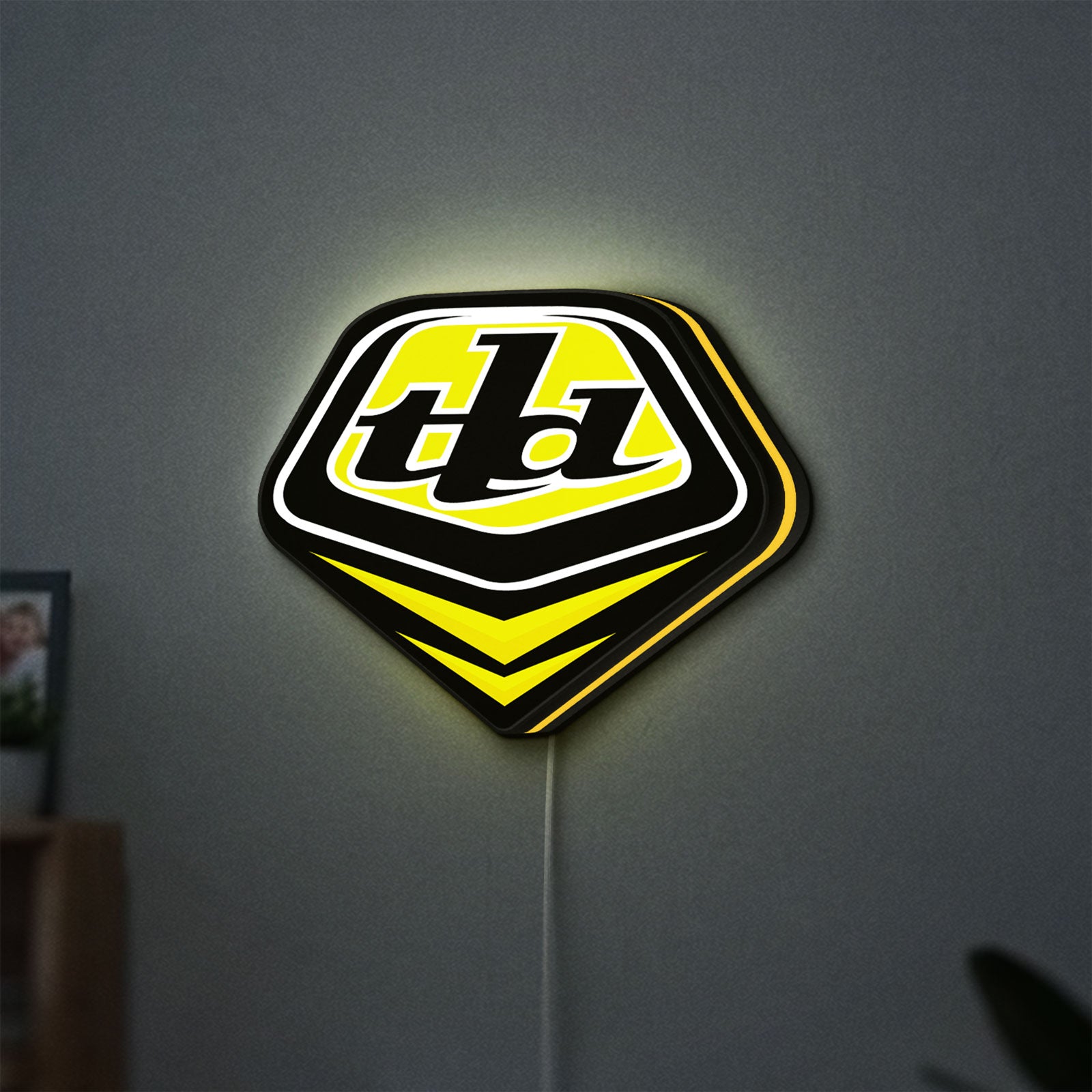 Troy Lee Designs LED lightbox hanging on a wall with yellow glow
