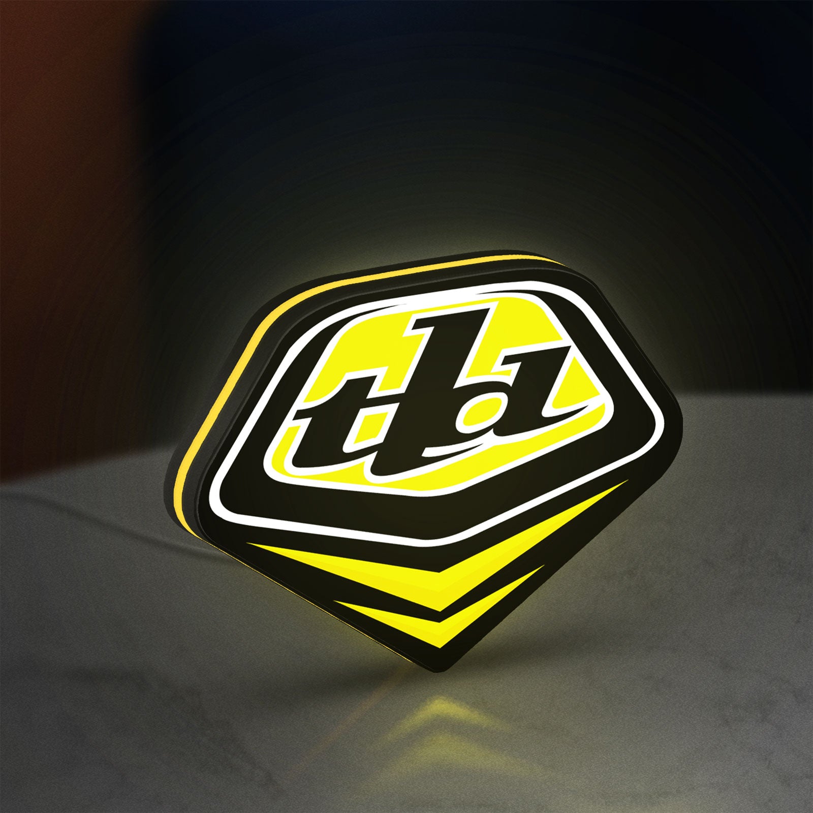 Troy Lee Designs LED lightbox standing on a desk from an angled side view with yellow glow