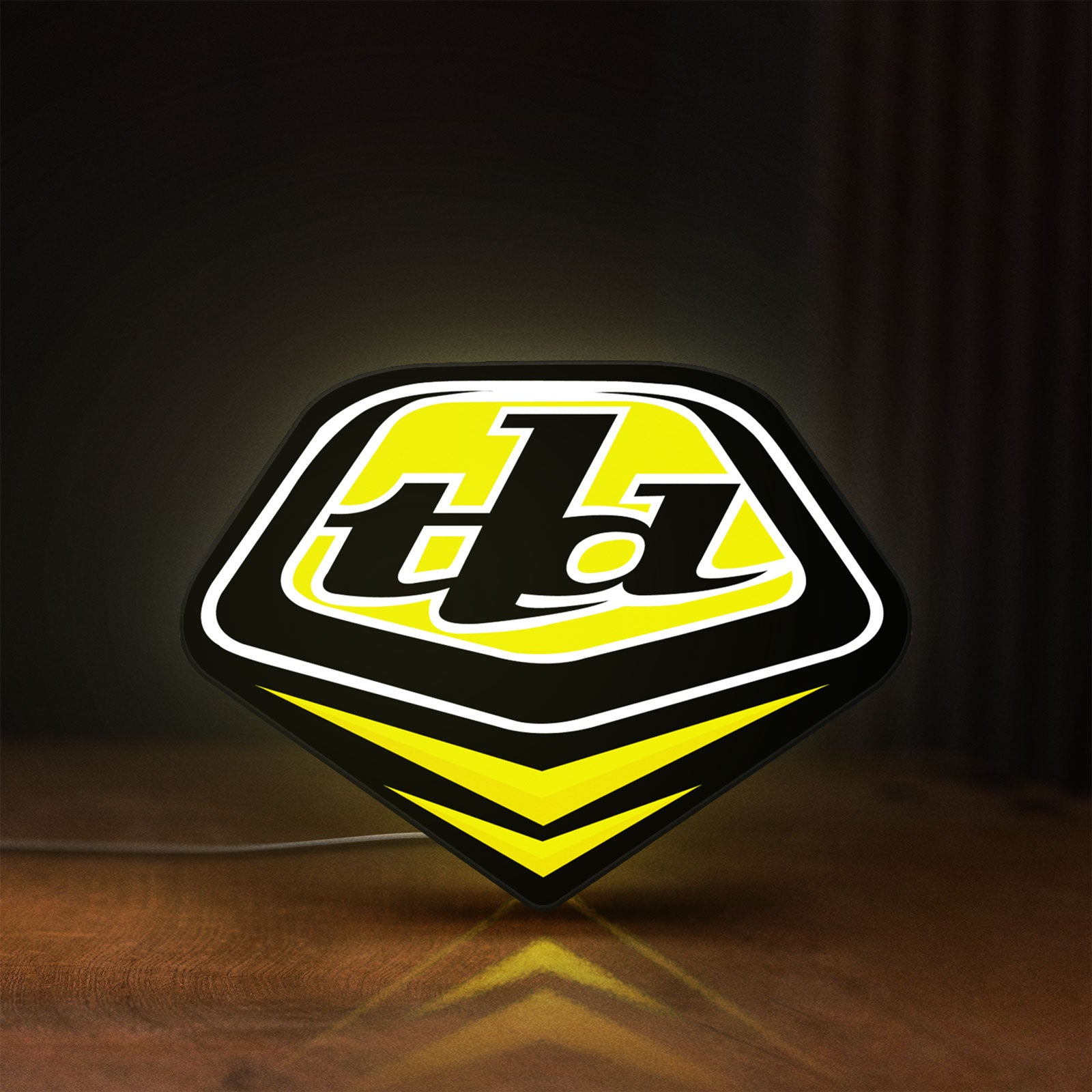 Front view of Troy Lee Designs LED lightbox sign glowing on a wooden desk