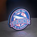 Tiburones De La Guaira LED lightbox standing on a desk from an angled side view with blue glow