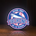 Front view of Tiburones De La Guaira LED lightbox sign glowing on a wooden desk
