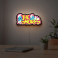 Smurfs LED lightbox hanging on a room wall with soft yellow light