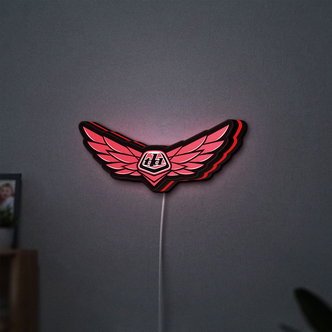 Troy Lee Designs LED lightbox hanging on a wall with red glow