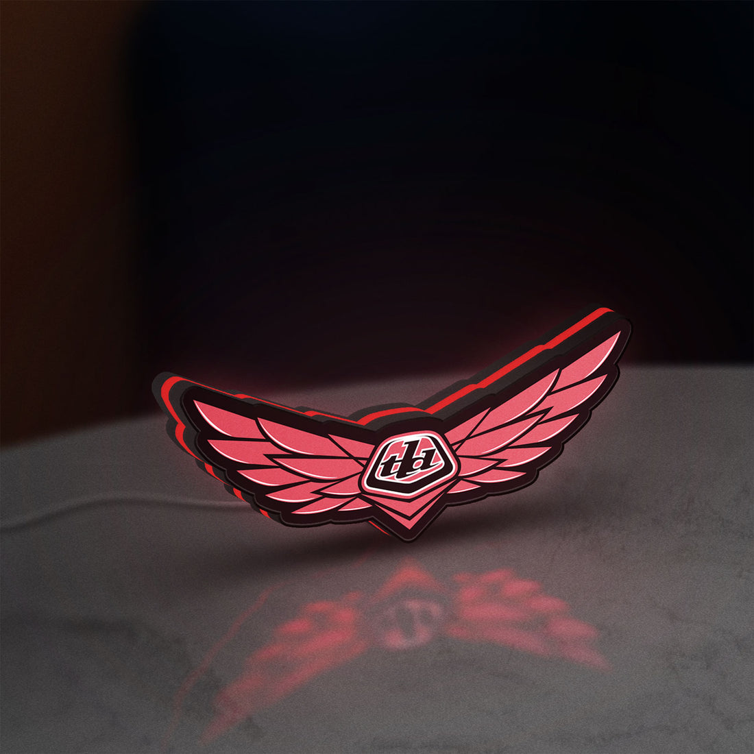 Troy Lee Designs LED lightbox hanging on a wall with red glow