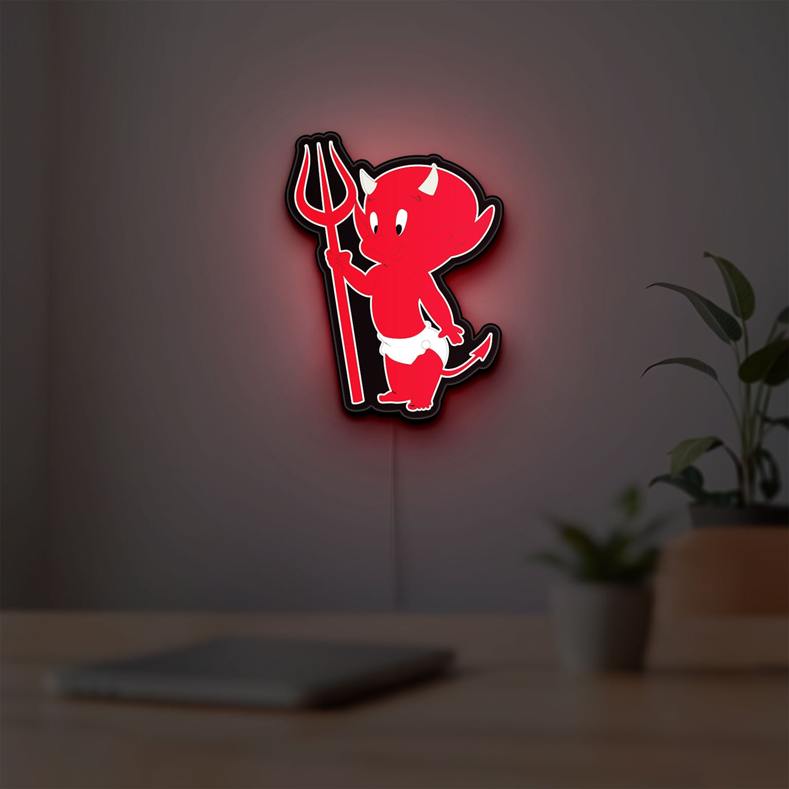 Little Devil LED lightbox hanging on a room wall with soft red light