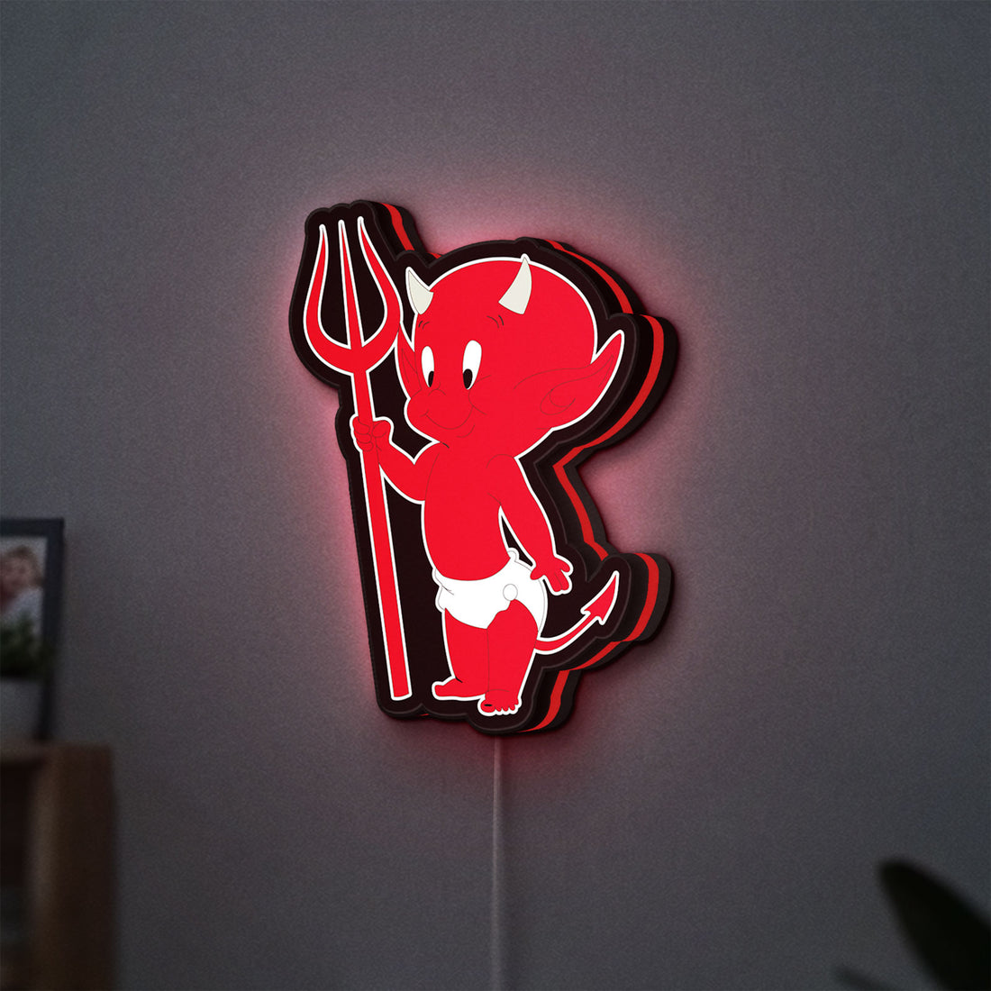 Little Devil LED lightbox hanging on a wall with red glow