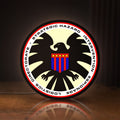 Front view of S.H.I.E.L.D. LED lightbox sign glowing on a wooden desk