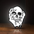 Front view of Skull LED lightbox sign glowing on a wooden desk