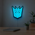 Decepticons LED lightbox hanging on a room wall with soft blue light