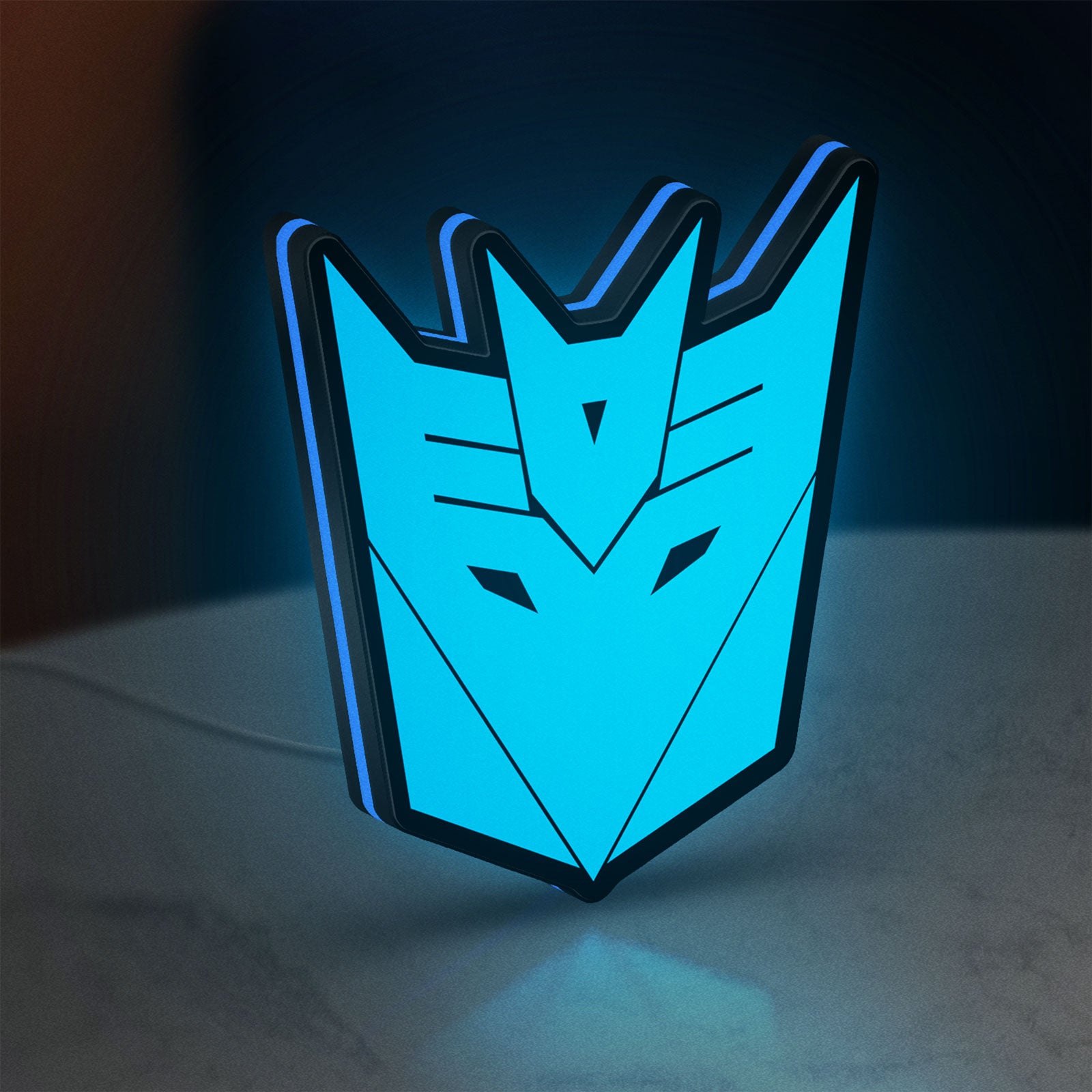 Decepticons LED lightbox standing on a desk from an angled side view with blue glow