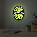 Teenage Mutant Ninja Turtles LED lightbox hanging on a room wall with soft green light