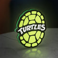 Teenage Mutant Ninja Turtles LED lightbox standing on a desk from an angled side view with green glow