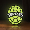 Front view of Teenage Mutant Ninja Turtles LED lightbox sign glowing on a wooden desk