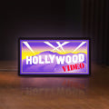 Front view of Hollywood Video LED lightbox sign glowing on a wooden desk