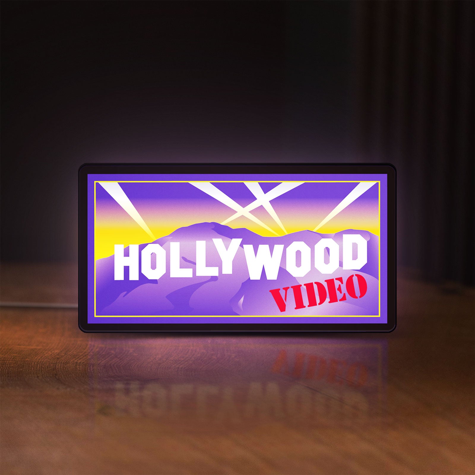 Front view of Hollywood Video LED lightbox sign glowing on a wooden desk