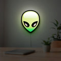 Alien LED lightbox hanging on a room wall with soft green light