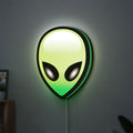 Alien LED lightbox hanging on a wall with green glow