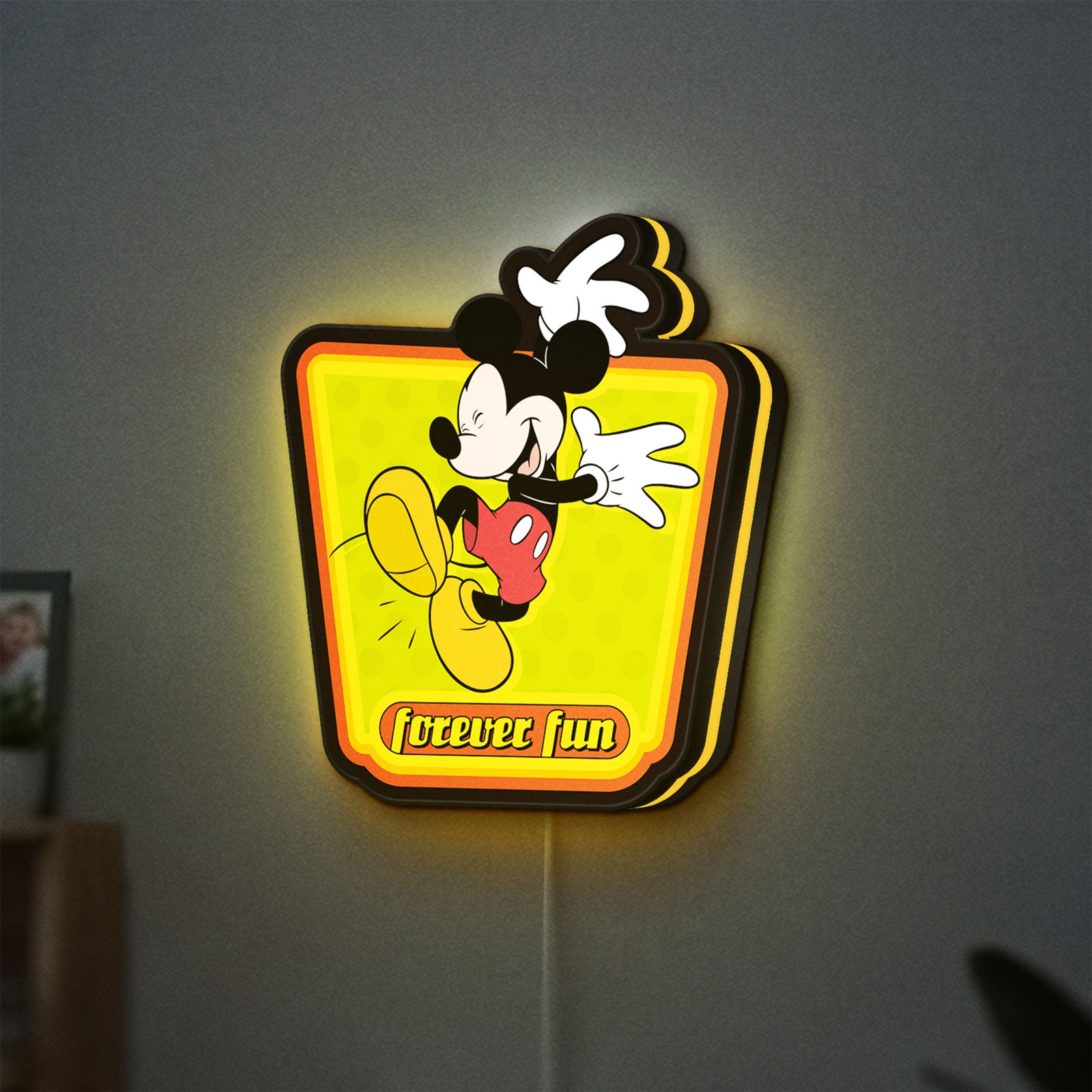 Mickey Mouse LED lightbox hanging on a wall with yellow glow