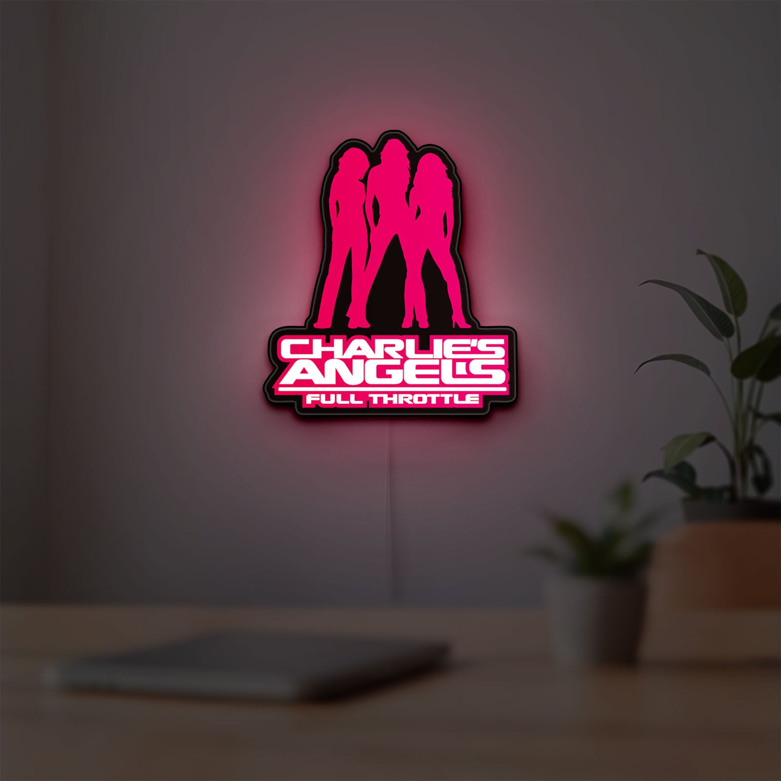 Charlie's Angels LED lightbox hanging on a room wall with soft pink light