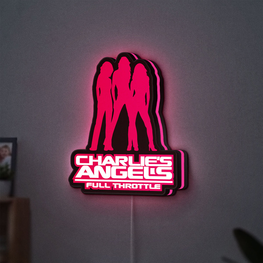 Charlie's Angels LED lightbox hanging on a wall with pink glow
