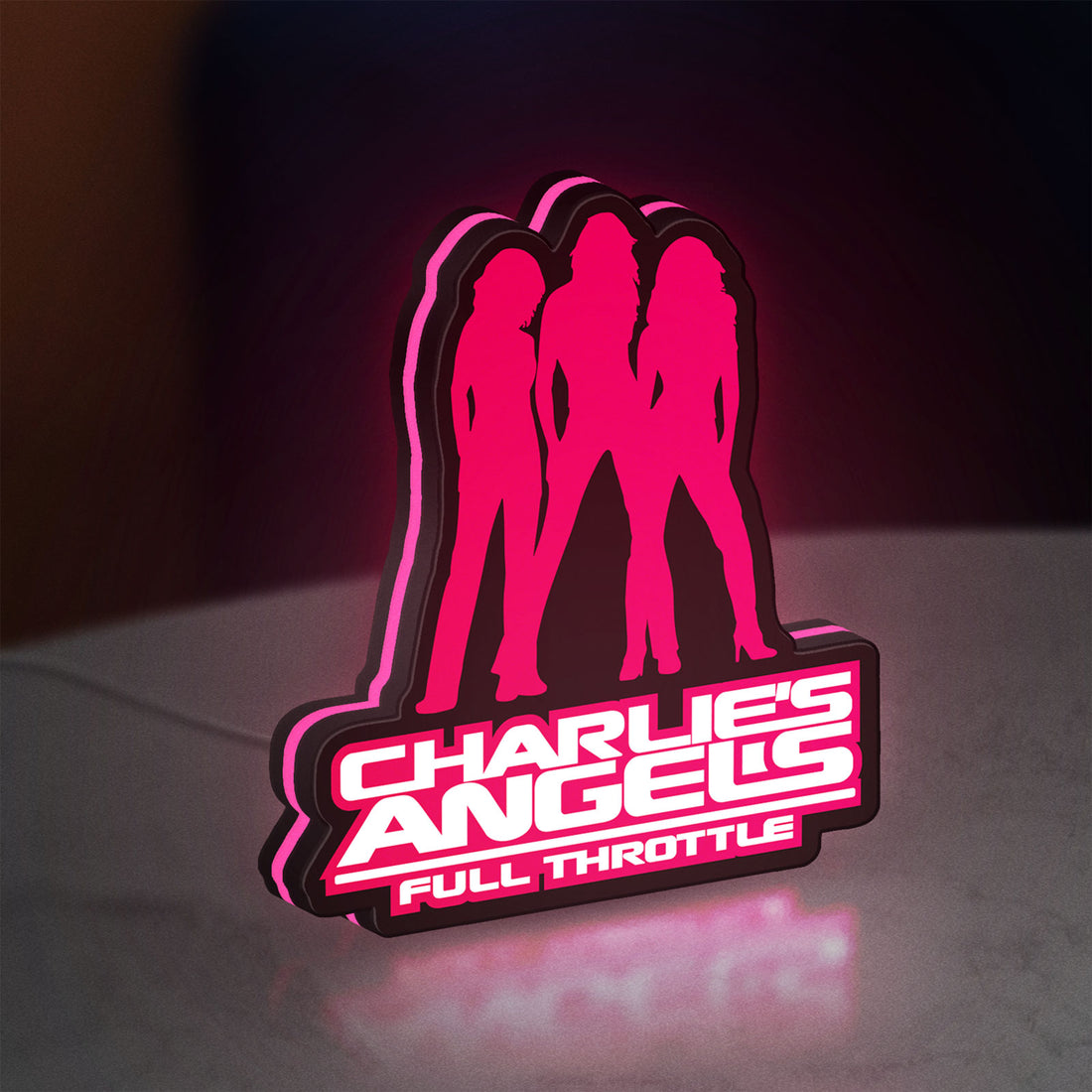 Charlie's Angels LED lightbox hanging on a wall with pink glow