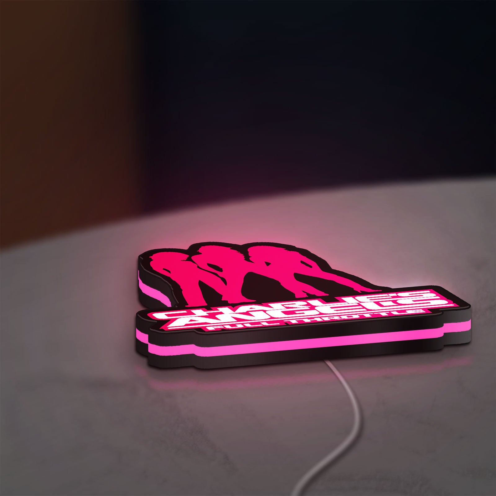 Charlie's Angels LED lightbox lying flat on a desk with pink glow
